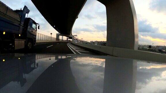黄昏时分在高速公路上开车汽车引擎盖上的摄像头行动相机拍摄