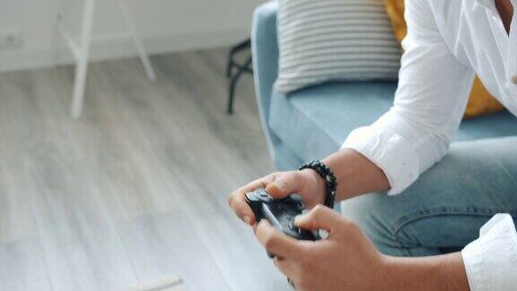 情感混合种族男子玩视频游戏的特写在家里按操纵杆按钮
