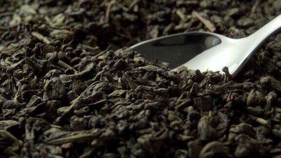 绿茶火药闪亮的甜点勺黑色的干燥的卷起来的中国茶叶与金属勺特写