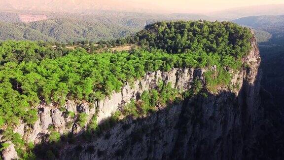 峡谷顶端茂密的神奇森林巨大壮观的悬崖岩石史诗般的无人机飞越山谷在4k美丽的戏剧性的地质奇迹与绿树鸟瞰
