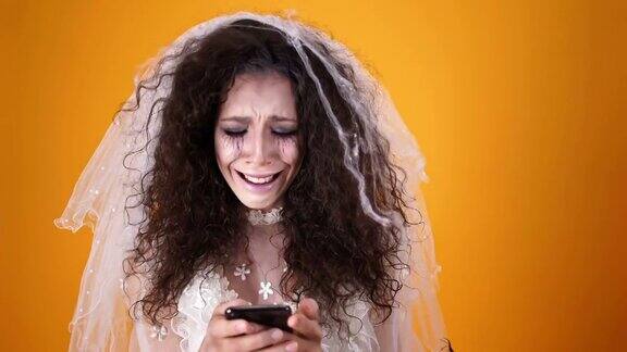 在万圣节哭丧的新娘穿着婚纱化着妆用智能手机