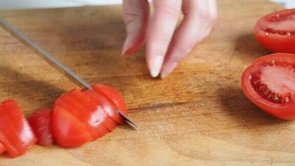 一位女厨师准备用新鲜蔬菜做健康沙拉素食在家庭厨房的木板上切番茄