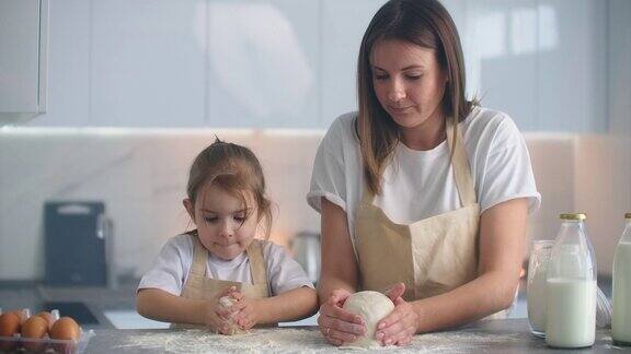 母亲和女儿在厨房用面团模具做饭母亲和女儿拿着心形的面团模具用你的手雕刻面团做比萨饼或馅饼饼干的空白