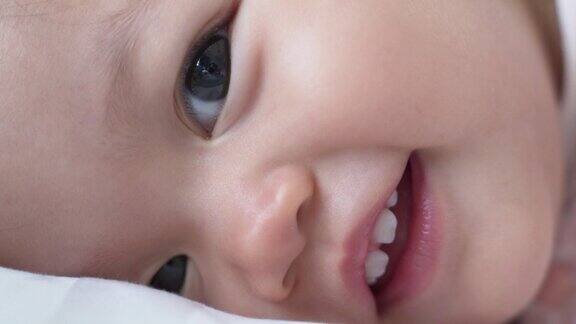 婴儿的特写:喝完奶瓶里的牛奶后婴儿眨着眼睛微笑孩子眨眼娃娃脸开心的笑亚洲的孩子