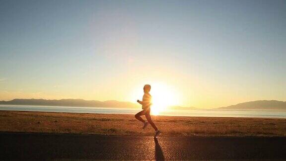 年轻的健身女子跑步在日出的海滨小径