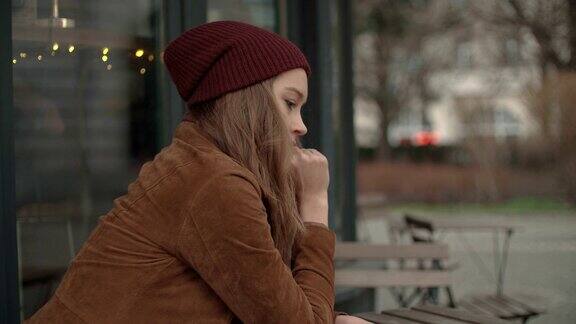 一个忧郁的白人女孩坐在露天咖啡馆里
