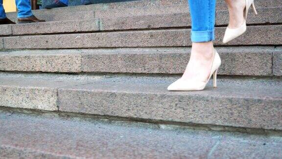 女腿穿着牛仔裤和时髦的高跟鞋走下楼梯迷人女孩纤细的脚踩在楼梯上年轻女子从楼梯上下来女孩走在城市的街道上慢动作