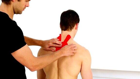 理疗师将红色肌内肌贴贴在病人的背部