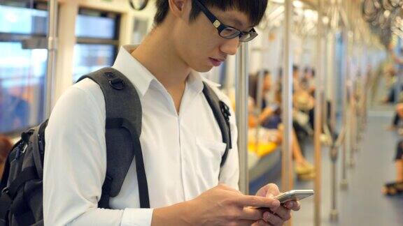 一名年轻人在火车上使用智能手机