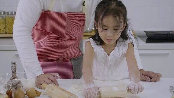亚洲家庭父亲教女儿学做面包女儿玩面团玩得很开心