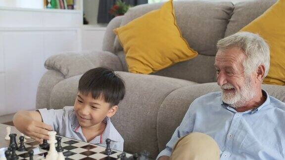 爷爷、老爷爷、小孙子和老爷爷一起笑着、开心地在客厅下棋