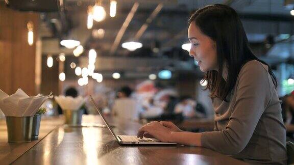 亚洲女人在咖啡馆使用笔记本电脑