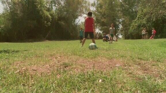 年轻快乐的孩子们在夏令营踢足球在绿色的草地上孩子们慢镜头空中垂直