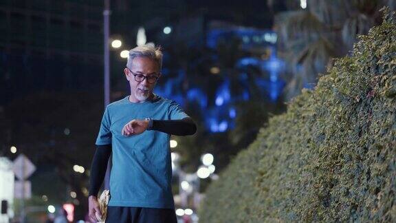 晚上下班后在城市慢跑后一名亚裔中国活跃老人用毛巾擦汗