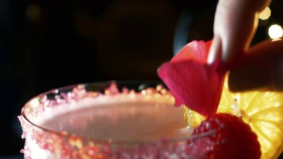 特写跟踪镜头的一个清爽的红色鸡尾酒在酒吧和一个女性的手装饰水晶玻璃与一朵花