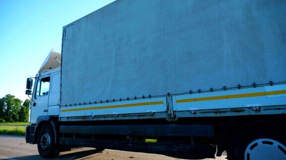 带货运拖车的卡车在高速公路上行驶并运输货物的侧视图穿过乡村公路开往目的地的卡车货物运输慢动作