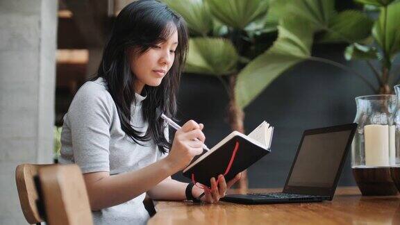 亚洲女性自由撰稿人正在写他的文章在一个笔记本上想法和灵感