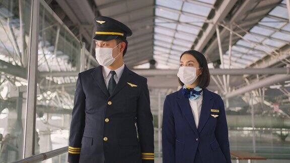 新冠肺炎疫情期间飞行员和空乘人员戴口罩走在机场航站楼走向飞机以预防新冠肺炎感染航空运输的新常态生活理念