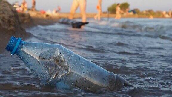 海滩上放着一个塑料瓶海浪冲刷着它特写慢动作防治环境污染的理念