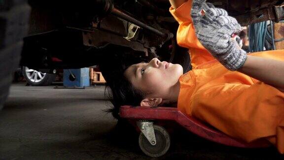 小车侧视图:亚洲年轻女性汽车机械师在汽车发动机下工作