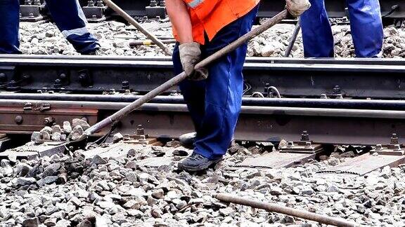 身穿制服手拿铁铲的铁路工人正在修理铁轨