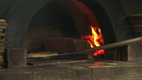 4K:厨师把披萨从披萨炉的砖里搬出来