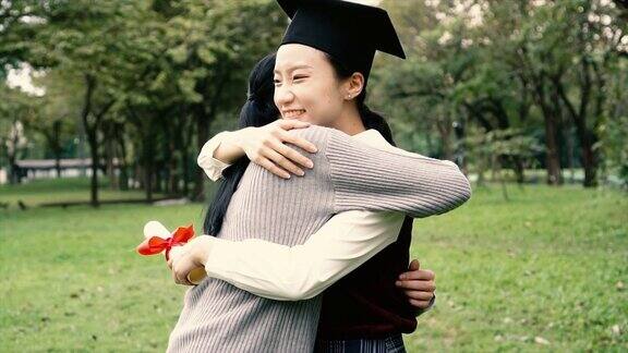 年轻的亚洲女毕业生拥抱她的朋友在毕业典礼的慢镜头国际多元化背景