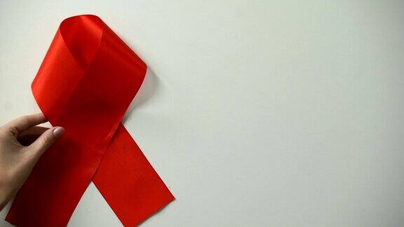 女性手把红丝带放在桌上艾滋病意识和预防健康