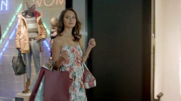 购物中心里拿着包的女人时尚女孩在购物中心看橱窗背景