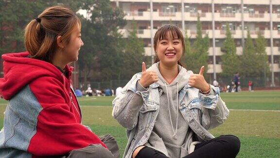 两位女大学生在校园的草地上聊天