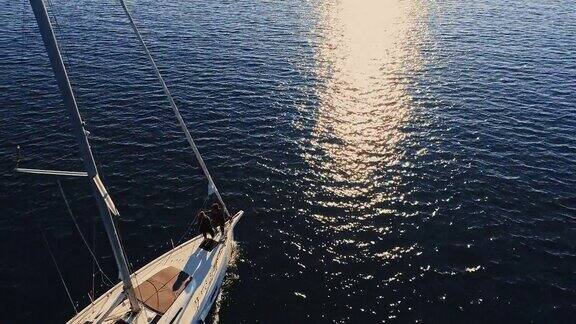日落时分两个人在帆船的甲板上享受微风
