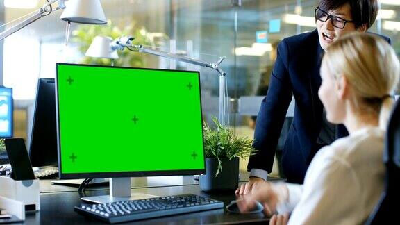 在办公室里女商人坐在她的办公桌前和她的经理谈话她的个人电脑显示模拟的绿色屏幕时尚办公室里的职业商务人士