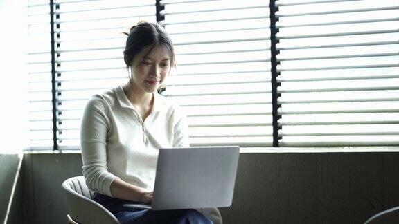 亚洲女学生通过互联网在线学习与导师在笔记本电脑上亚洲妇女快乐的微笑打字工作在家概念在线学习