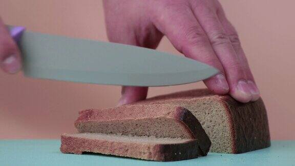 男性用手将黑麦面包慢动作切成块