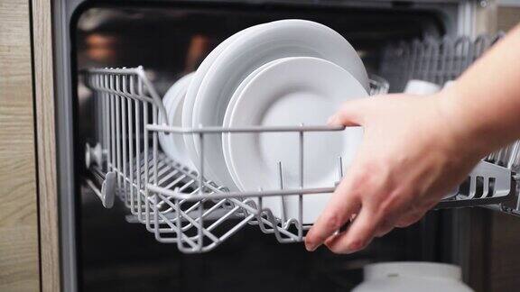 女性手从洗碗机的篮子里取出洗好的盘子从打开的机器中取出