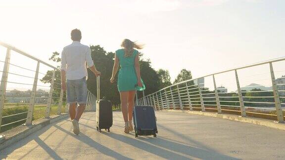 拷贝空间:日落时分年轻的新婚夫妇提着他们的行李箱去机场