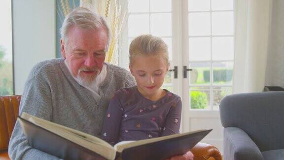 爷爷和孙女在家里的休息室一起看相册