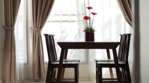 带花瓶的木桌模糊了帘窗与绿色花园摄影车从右向左拍摄
