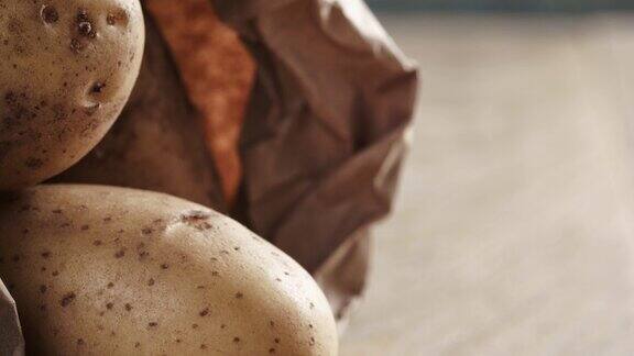 牛皮纸袋里的新鲜土豆放在橡木桌子上