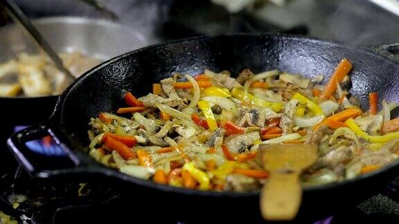 厨师在厨房用锅煎蔬菜和肉