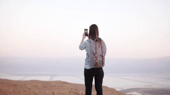 一个女人在拍摄山景缓慢的运动用智能手机背包的休闲旅行者女孩以色列死海