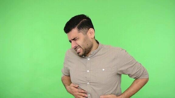 胃痛生病的棕发男子腹痛腹部肿胀工作室拍摄绿色背景