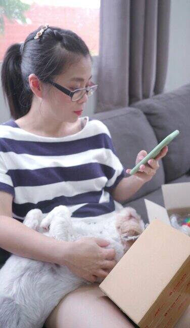 一个女人坐在沙发上用智能手机打字客厅里还有一只狗