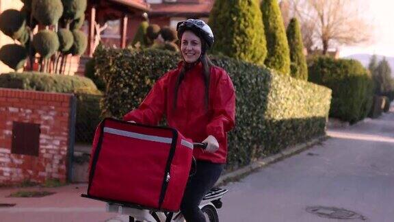 快乐的送餐女骑着自行车在居民区送餐