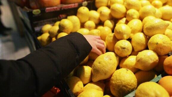 年轻女子在超市挑选从有机农场采摘的新鲜柠檬一个迷人的年轻女孩的手与水果在它的特写
