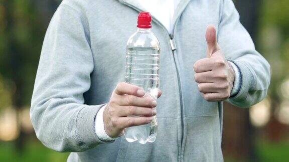 运动员翘着大拇指举着瓶子喝饮料每天饮水