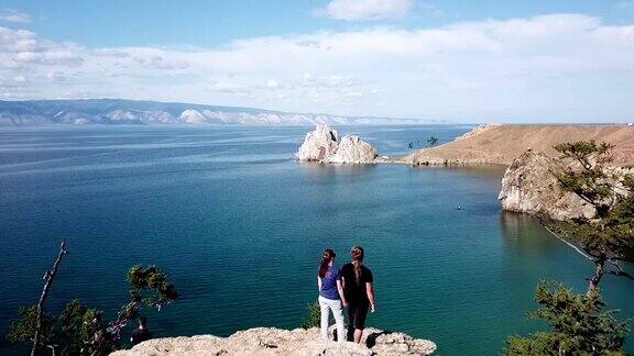 一个男人和一个女人站在海边的悬崖上贝加尔湖无人机空中拍摄