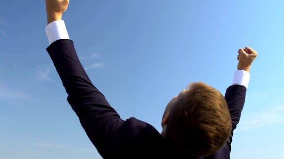 兴奋的男CEO摆出成功的姿态举起双手事业晋升