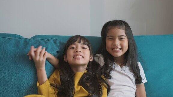 两个亚洲女孩是朋友微笑在沙发上