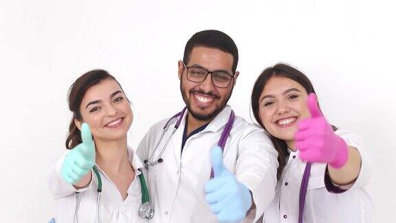 三个微笑的年轻医护人员看着摄像机竖起大拇指